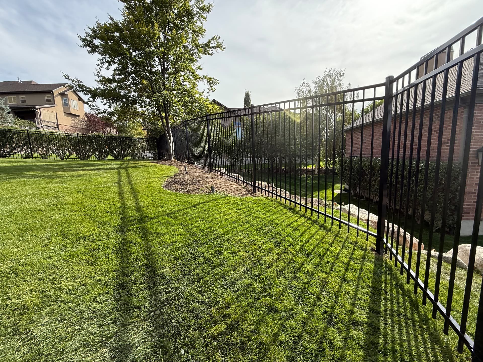 Black ornamental aluminum fence around a manicured Utah backyard lawn